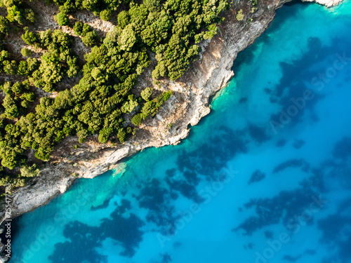 Scenic aerial top down view of picturesque jagged coastline of Kefalonia with clear turquoise waters, surrounded by steep cliffs.