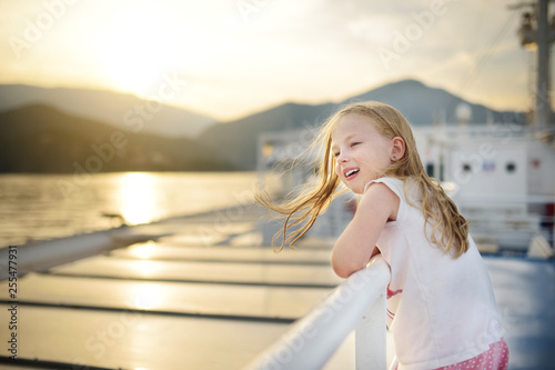 Fototapeta Naklejka Na Ścianę i Meble -  Adorable young girl enjoying ferry ride staring at the sea on sunset. Child having fun on summer family vacation in Greece.
