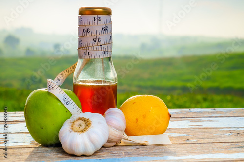 Fresh organic honey in glass jar , measuring tape, green epal , lemon and garlic on old wooden with blurred background , healthy nutrition, strengthening immunity, diet and treatment of flu photo