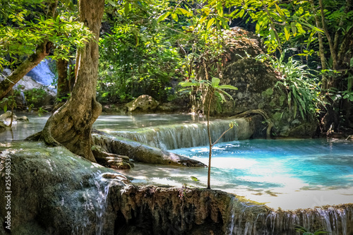 Closeup of a clear blue pool of water and a short waterfall in Erawan National Park