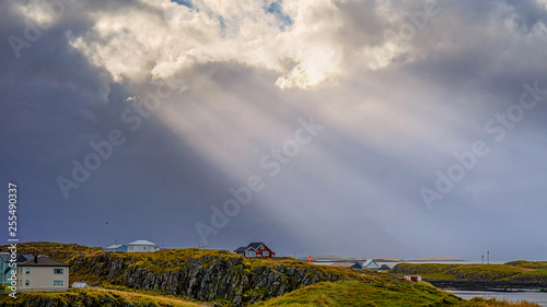 Beautiful traditional houses in Stykkisholmur the harbour village with cloudy sky and sun ray to the village , Iceland. photo