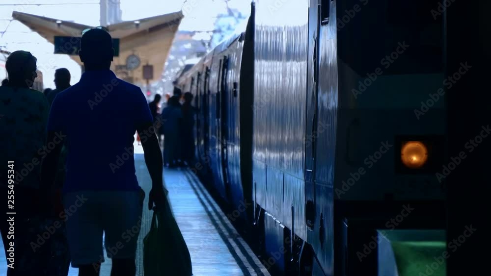 At the rail station, at the platform there are two trains and passengers are calmly walking and standing on the platform - it is not yet time for the train to departure