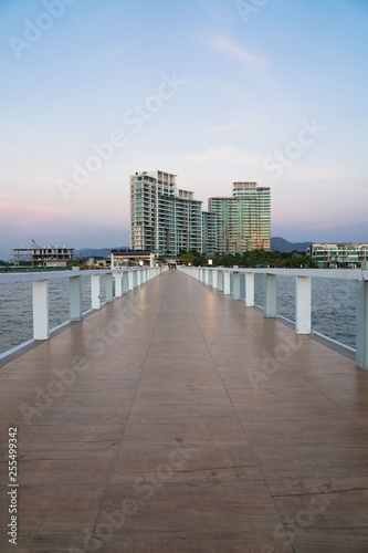Landscape of bridge in sea on tropical beach and building and sunset sky background .