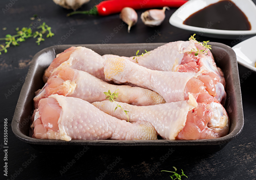 Raw uncooked chicken legs, drumsticks on dark table. Chicken meat with ingredients for cooking. Raw uncooked chicken legs, drumsticks on dark table. Chicken meat with ingredients for cooking.
