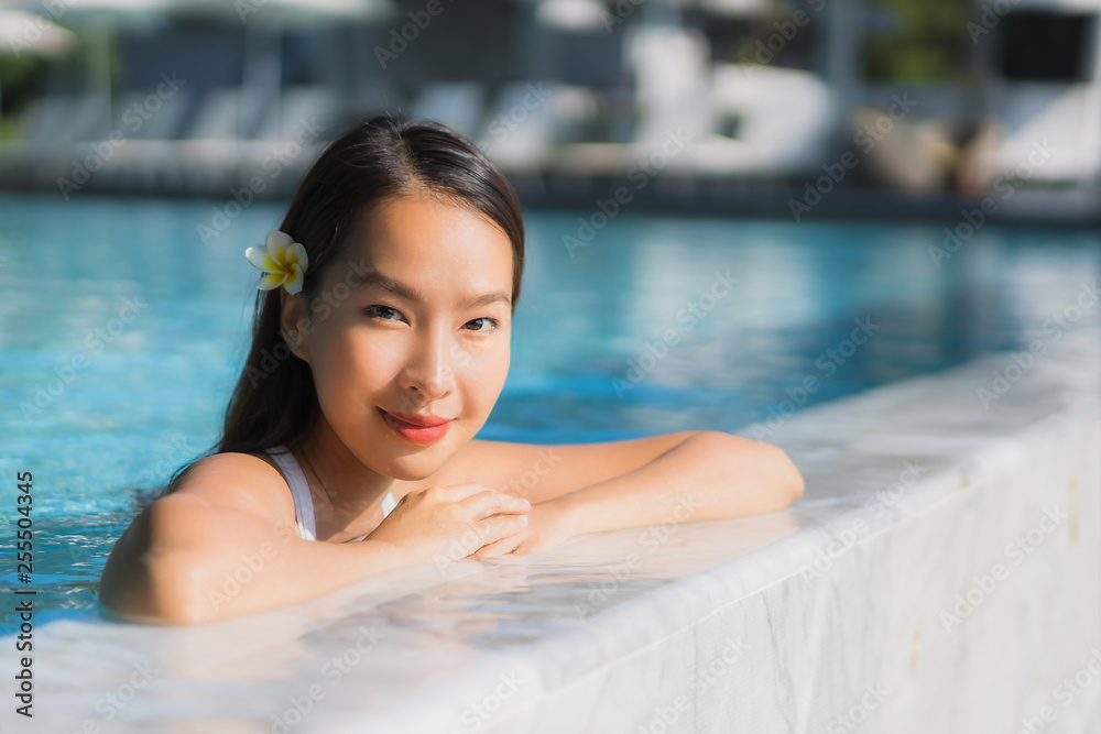 Portrait beautiful young asian woman happy smile in swimming pool around resort and hotel