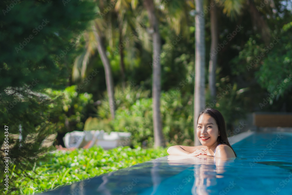 Portrait beautiful young asian woman happy smile in swimming pool around resort and hotel