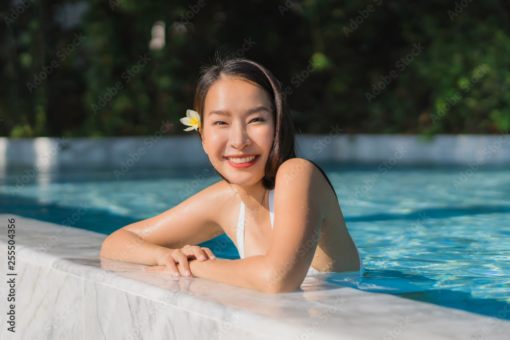 Portrait beautiful young asian woman happy smile in swimming pool around resort and hotel