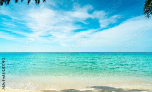 Golden sand beach by the sea with emerald green sea water and blue sky and white clouds. Summer vacation on tropical paradise beach concept. Ripple of water splash on sandy beach. Summer vibes.