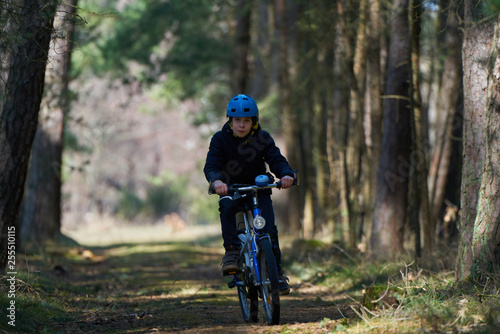 Boy with blue helmet rides a bicycle in forest