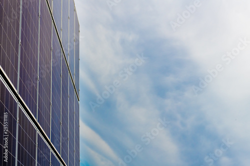 Solar cell photovoltaic panels at energy production plant with blue cloudy sky in the background