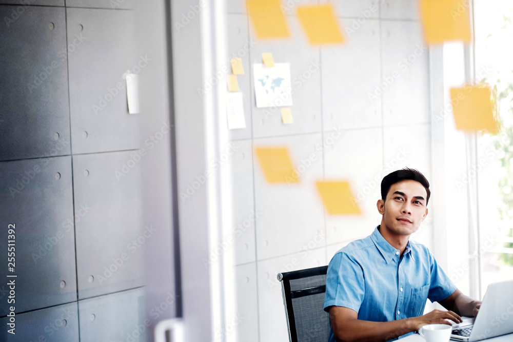 Young Asian Businessman Working on Computer Laptop in Office Meeting Room. Man Analyzing Data Plans and Project. Concentrate on Document Note on Board Young Asian Businessman Working on Computer Laptop in Office Meeting Room. Man Analyzing Data Plans and Project. Concentrate on Document Note on Board
