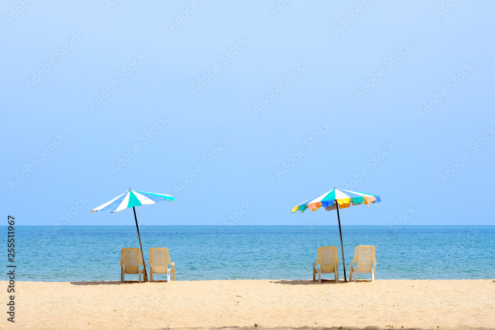 Fototapeta premium Summer background, chair and colorful umbrella on beach and sea background with copy space