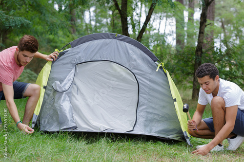 male friends setting up tent outdoors