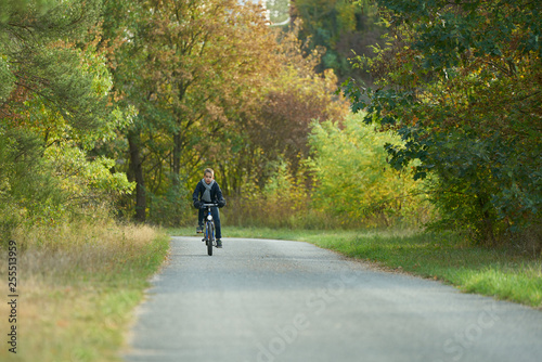 Boy with blue jacket rides a bicycle on an autumn day in the forest
