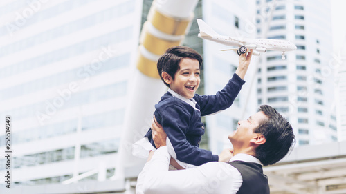 Father carries son playing aviator toy air plane imagination dreaming of being a pilot future on business district urban, Dad and Son happy family concept