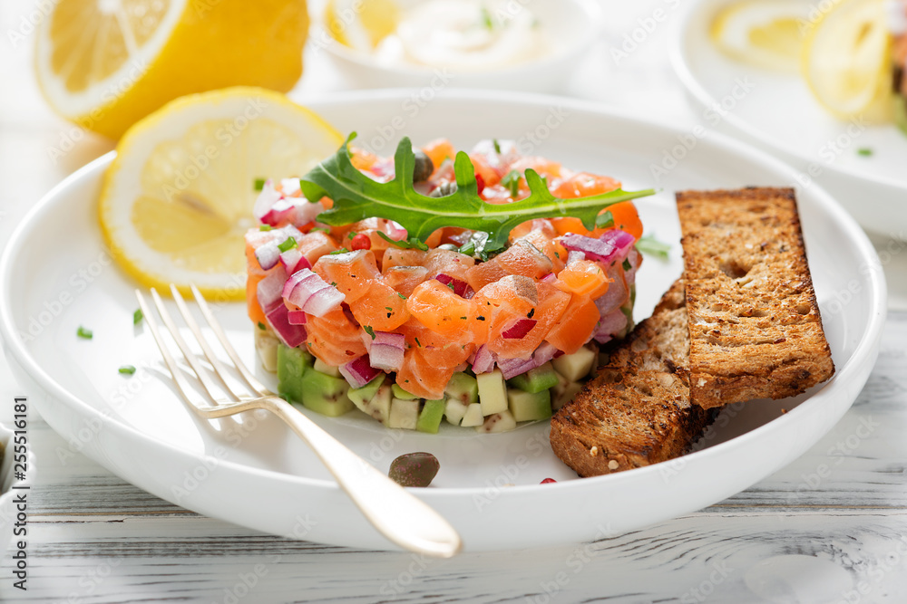 Salmon tartare with red onion, avocado, arugula and bread toast. Salmon tartare with red onion, avocado, arugula and bread toast.