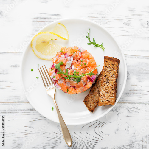 Bild auf Leinwand Salmon tartare with red onion, avocado, arugula and bread toast.