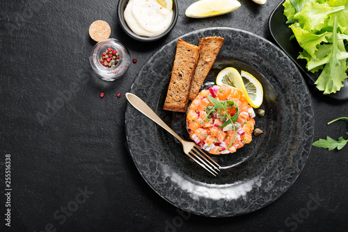Cuadro en lienzo Salmon tartare with red onion, avocado, arugula and bread toast.
