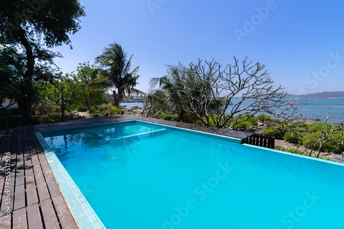 Swimming pool blue water and tropical garden with sea view background