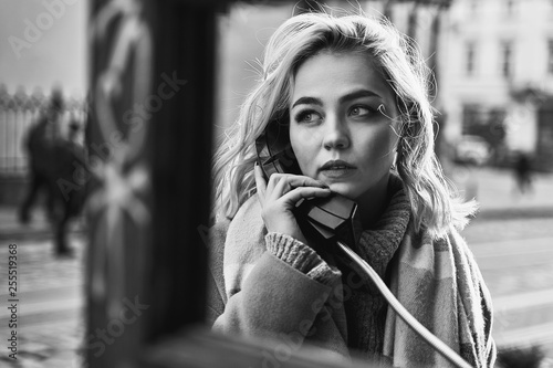 Obraz na płótnie Young beautiful blond woman making an important call in a vintage public phone booth on a sunny evening w salonie