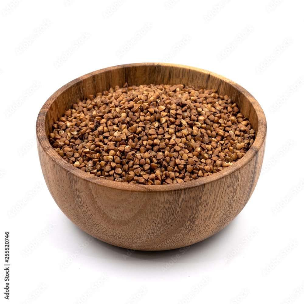 Raw buckwheat in a wooden plate isolated on white background Raw buckwheat in a wooden plate isolated on white background
