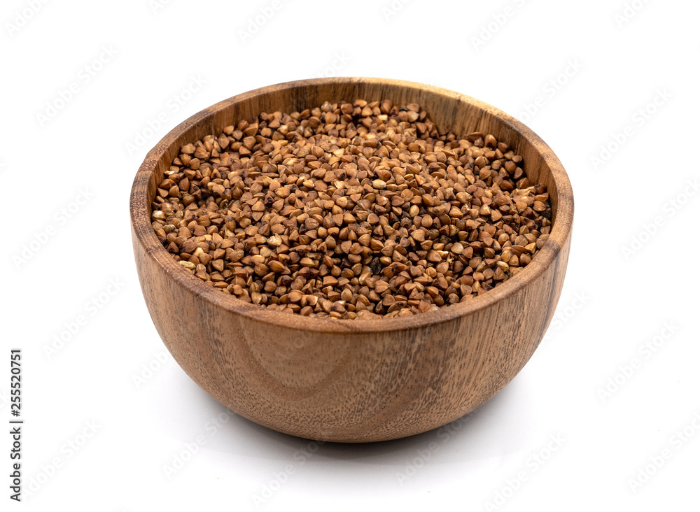 Raw buckwheat in a wooden plate isolated on white background Raw buckwheat in a wooden plate isolated on white background
