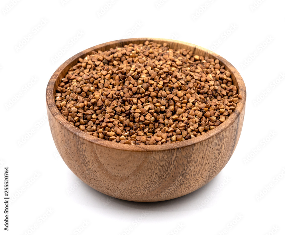 Raw buckwheat in a wooden plate isolated on white background Raw buckwheat in a wooden plate isolated on white background