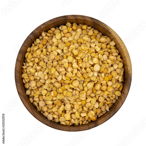 Raw yellow split peas in a wooden plate (bowl) isolated on white background, top down view