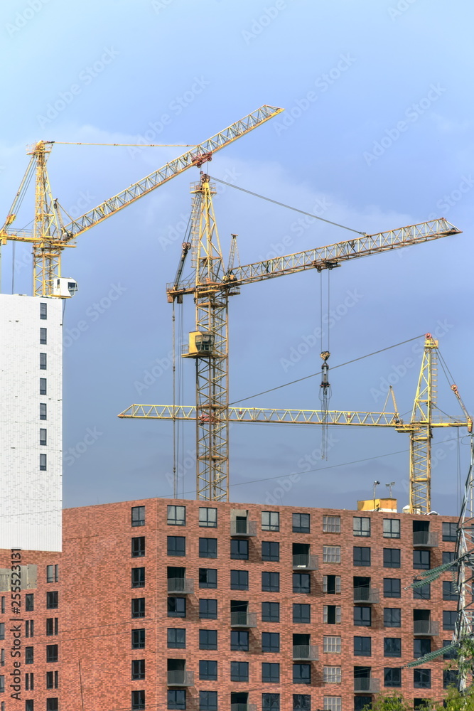 Large construction cranes working on a building complex. Space for text. Large construction cranes working on a building complex. Space for text.