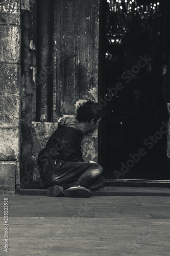 A homeless person is sitting near the temple.