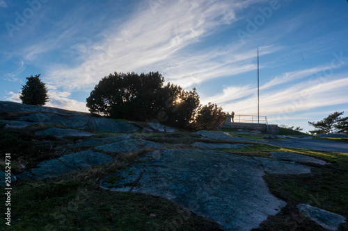 Man standing on top of ramberget hill with sunrays peeping through bush next to him photo