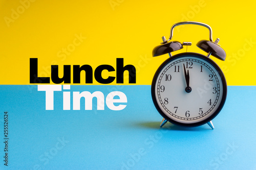 LUNCH TIME inscription written on Alarm Clock on blue yellow background. Business and motivation concept