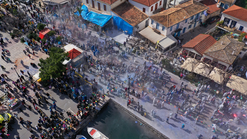 Aerial drone bird's eye view photo of people participating in traditional colourful flour war or Alevromoutzouromata part of Carnival festivities in historic port of Galaxidi, Fokida, Greece photo