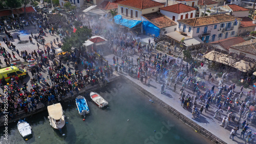 Fototapeta Naklejka Na Ścianę i Meble -  Aerial drone bird's eye view photo of people participating in traditional colourful flour war or Alevromoutzouromata part of Carnival festivities in historic port of Galaxidi, Fokida, Greece