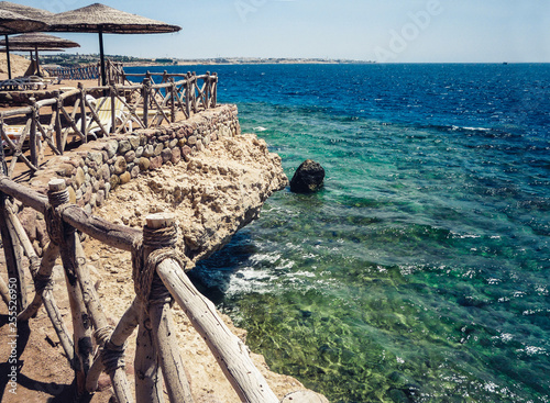 coast of the Red Sea with a wooden fence and sun umbrellas in Sharm El Sheikh, Egypt.