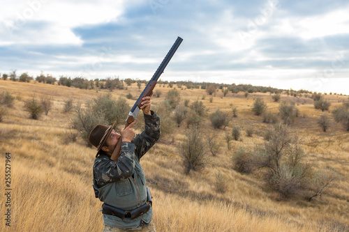 Hunter with a hat and a gun in search of prey in the steppe 