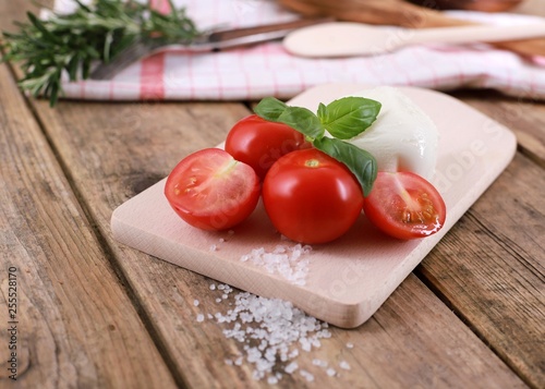 tomato mozzarella - fresh tomatoes with mozzarella cheese and basil  on a rustic wooden table