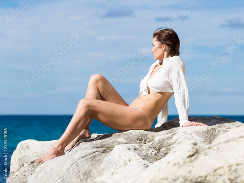 Female person resting on wild rocky seashore