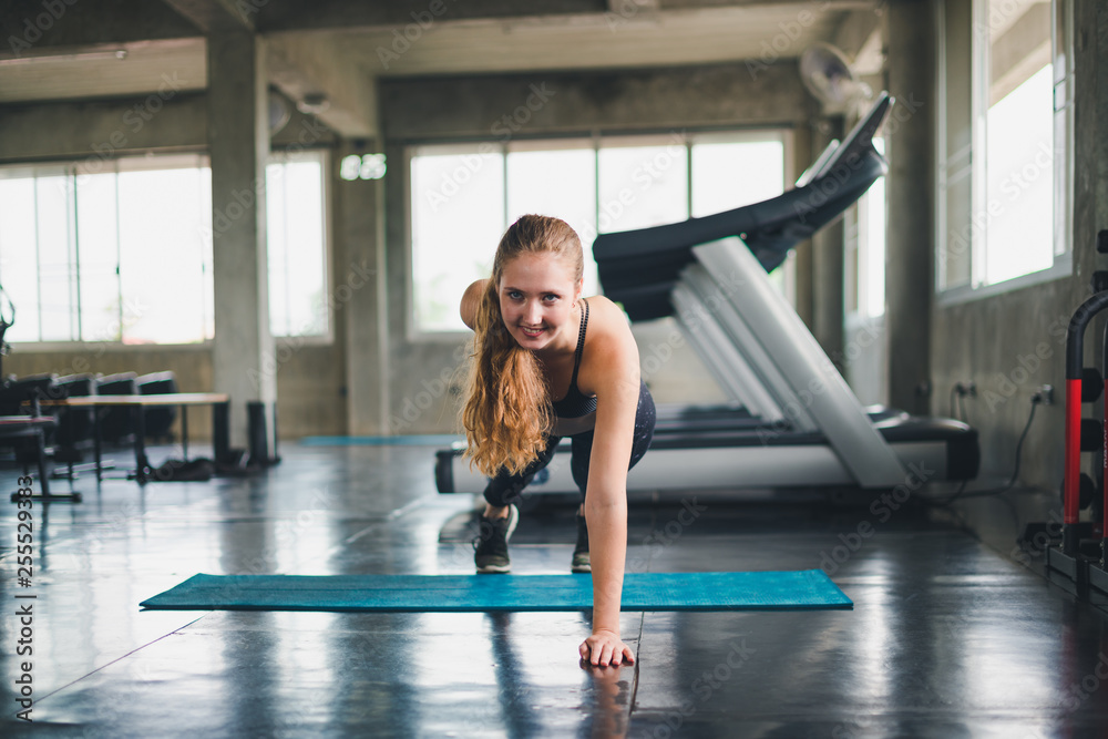 Beautiful athlete put on a sports suit. Stretching a muscle on a yoga mat. Before playing sports in the gym. She is relaxing Beautiful athlete put on a sports suit. Stretching a muscle on a yoga mat. Before playing sports in the gym. She is relaxing