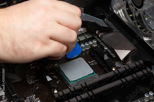 Work to collect a personal computer. Male hand applies thermal grease to the processor.