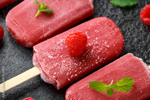 Homemade raspberry popsicles, ice lolly on rustic black background