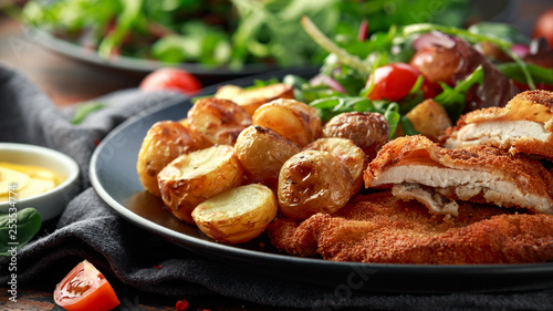 Tableau sur toile Homemade breaded pork schnitzel with roast potato and vegetables