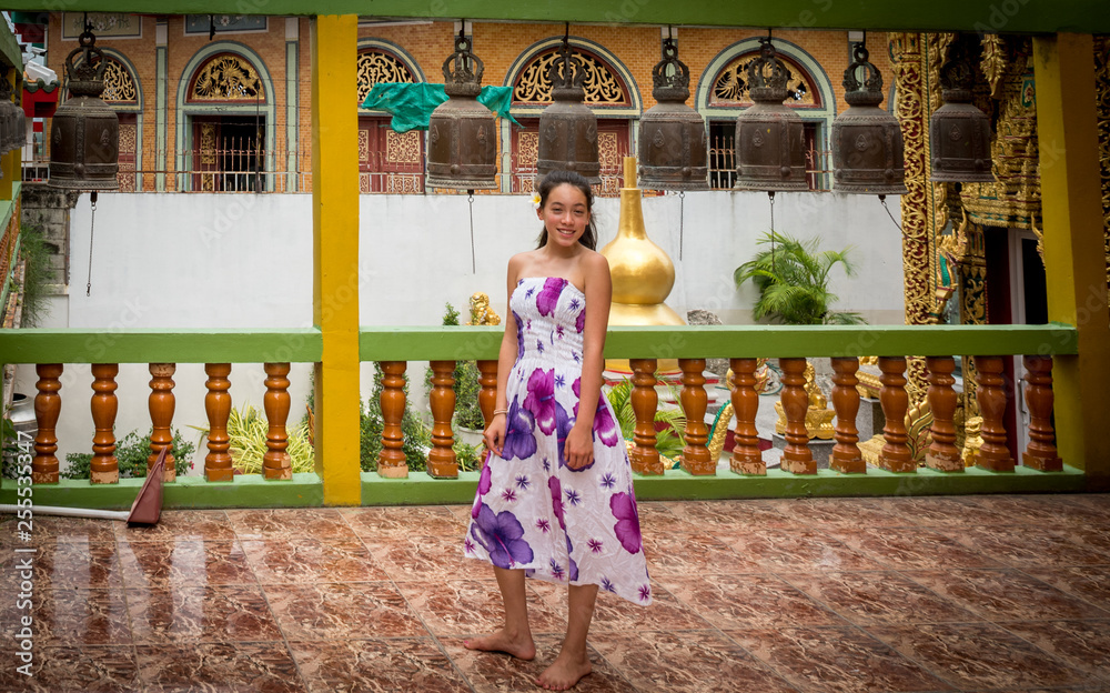 Teenage girl standing barefoot in front of row of bells