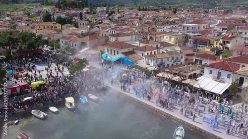 Aerial drone bird's eye view video of people participating in traditional colourful flour war or Alevromoutzouromata part of Carnival festivities in historic port of Galaxidi, Fokida, Greece photo