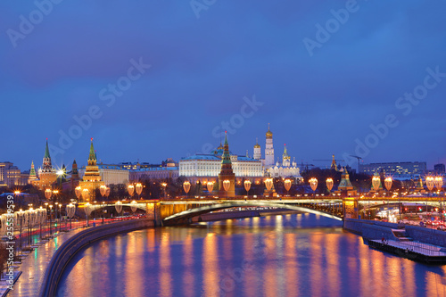 Illuminated Moscow Kremlin and Bolshoy Kamenny Bridge in the rays of setting sun. View from the Patriarshy pedestrian Bridge in Russia. Evening urban landscape in the blue hour