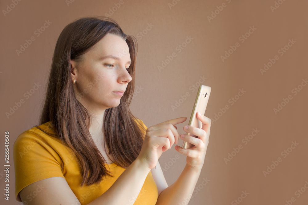 technology concept - smiling young woman in blank yellow t-shirt using smartphone technology concept - smiling young woman in blank yellow t-shirt using smartphone