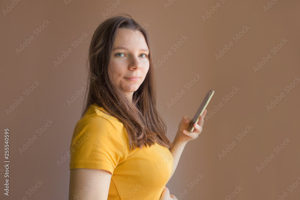 technology concept - smiling young woman in blank yellow t-shirt using smartphone technology concept - smiling young woman in blank yellow t-shirt using smartphone