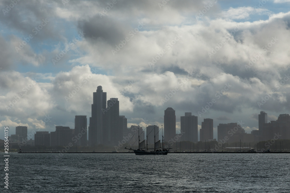 Old sailboat on Lake Michigan in front of marina and Chicago skyline during cloudy day Old sailboat on Lake Michigan in front of marina and Chicago skyline during cloudy day