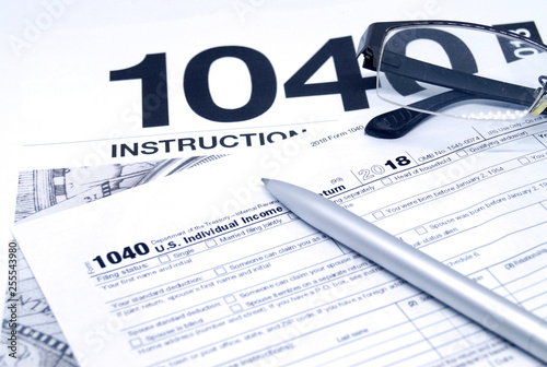 Income tax form with instruction, glasses and pen