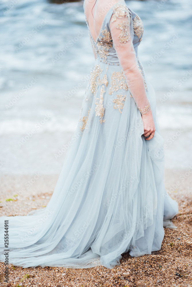 bride in a blue light dress walking along the ocean bride in a blue light dress walking along the ocean